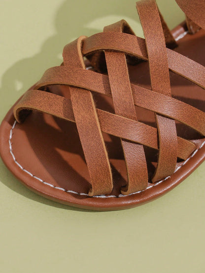 1 Pair Children's Brown Sandals, Solid Color PU Criss-Cross Woven Straps, Buckle Closure, Round Toe Open Toe Flat Non-Slip Fashion Cute Roman Sandals, Suitable For 3-12 Years Old Boys And Girls, Daily